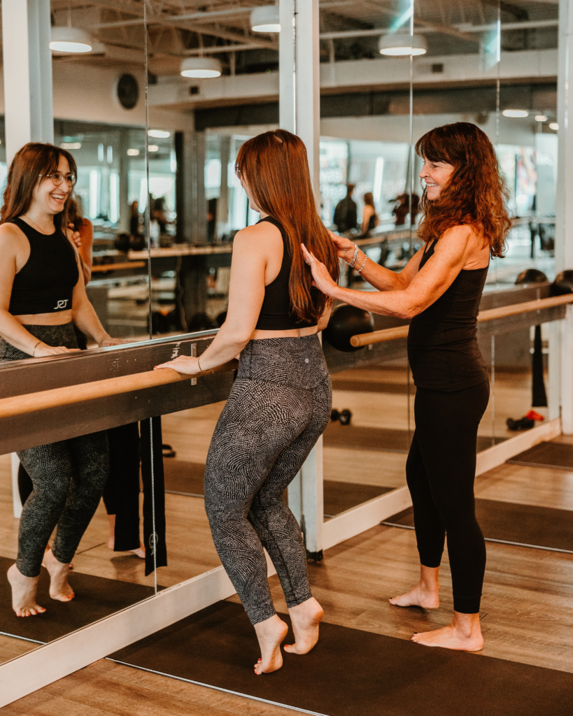 Barre Fitness Class at The Sweat Lab Durham NC Barre instructor correcting form during a barre class at The Sweat Lab in Durham, NC